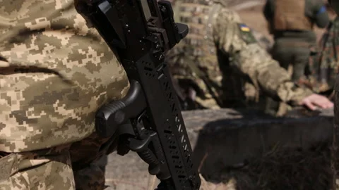 An armed soldier guards an object at a checkpoint with a submachine gun that he 库存影片 202610517