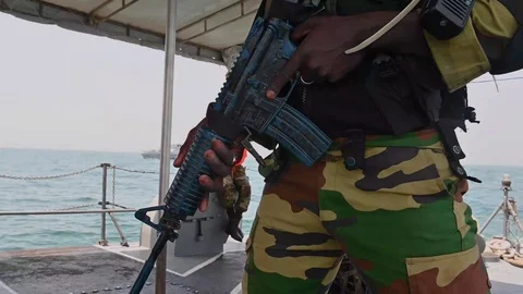 Armed soldier keeps watch aboard patrol vessel during Exercise Obangame Express Vídeos de archivo 105646783