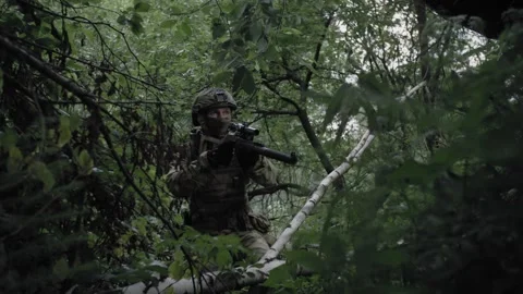 Armed soldier with a sniper rifle, in a dense forest, spotting an enemy Stock Footage 327288849