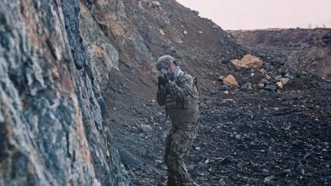 Armed soldier walking over large rocks. Stock Footage 144994938