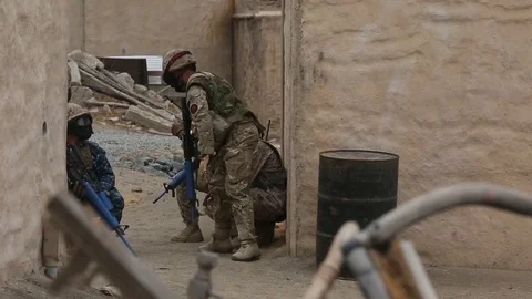 Armed soldiers kneeling while patrolling streets Stock Footage 90048202