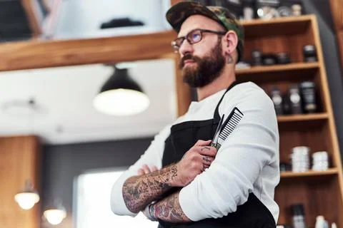 Armored up and ready to work. a handsome young barber posing with his arms Stock Photos