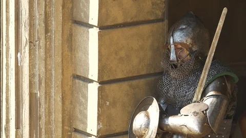 Armored warrior is resting in shadow of stone arena wall In waiting of the fight Stock Footage 100152047