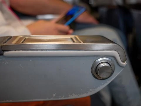 Armrest with button to control reclining back of a passenger seat in a plane. Stock Photos