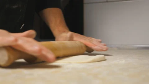 Arms of cook unrolling pastry using rolling pin on a kitchen table at restaurant Video stock 146636749
