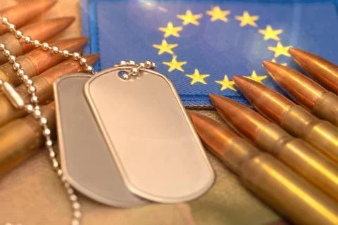 Army ammunition and identification tags lie on camouflage fabric next to Euro Photos