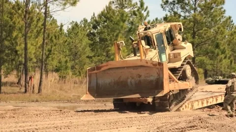 Army bulldozer being driven off trailer onto sandy road Stock Footage 271338516