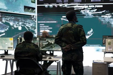 Army conscript examining crucial real time data on a big screen 库存照片