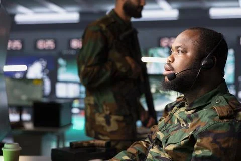 Army dispatcher relaying data to troops using headset mic 스톡 사진