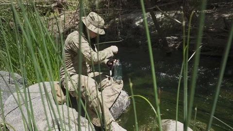 Army man pumping water through filter from a stream into clean drinking water Stock Footage 122097269