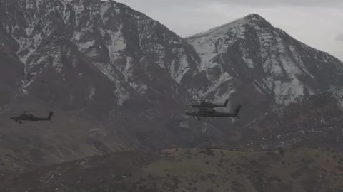 Army National Guard AH-64E Apache Guardians flying near snow capped mountains Vídeos de archivo 295275953