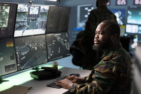Army operator tracking enemy troops coordinates on surveillance screens Stock Photos