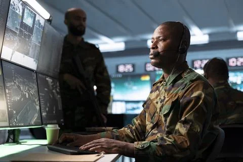 Army operator using radio telecommunications next to armed soldier Stock Photos