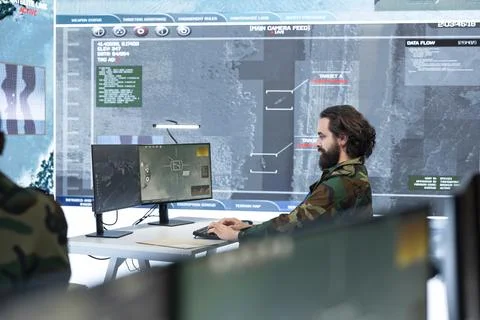 Army operator works at computer desk, analyzing intelligence feed Stock-Fotos
