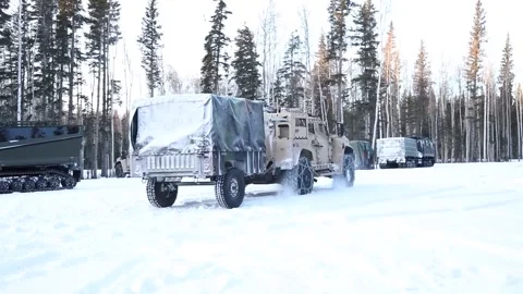 Army Oshkosh JLTV driving over snow covered ground with snow chains fitted Stock Footage 260312708