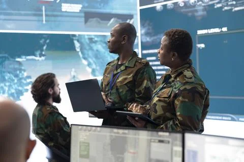 Army personnel compare intelligence data on laptop in command center Stock-Fotos