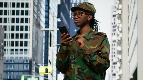 Army soldier examines smartphone map app and walking on city street Stock Footage 334173069