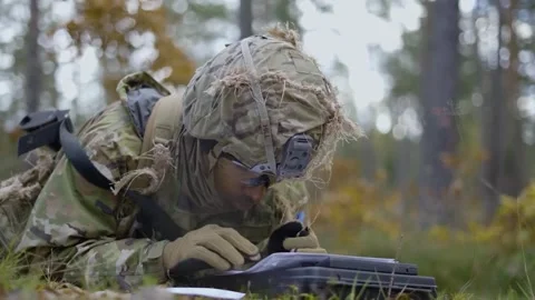 Army soldier mapping route while lying in forest Stock Footage 255204018