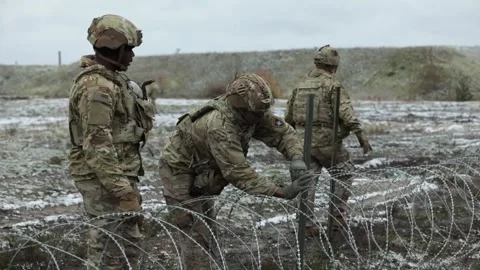 Army soldier secures razor wire to post Stock Footage 254403148
