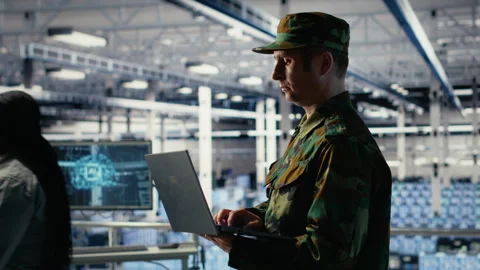 Army soldier in server farm uses artificial intelligence program on laptop Stock Footage 314804005