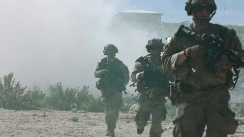 Army soldiers using smoke screen to advance on foot through desert terrrain Stock Footage 268823910