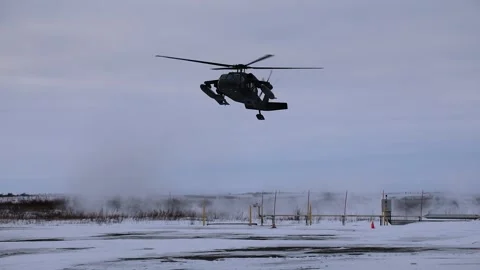 Army UH-60 Black Hawk approaching snow covered airfield with skids attached Stock Footage 293684804