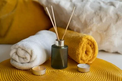 Aroma diffuser bottle with orange and white towels and candles on orange carp Stock Photos