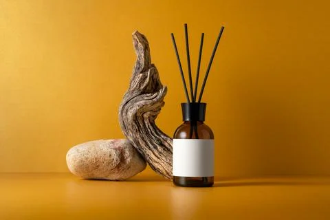 Aroma diffuser in brown glass bottle on stone podium with sticks, driftwood a 库存照片
