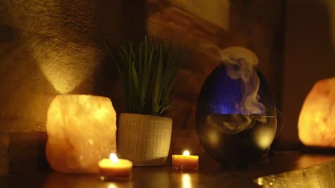 Aroma electric oil diffuser lamp, candles on wooden table in room. 4k, Video stock 129298231