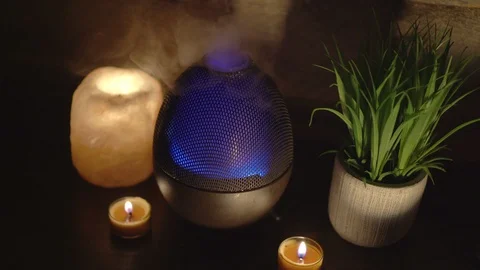 Aroma electric oil diffuser lamp, candles on wooden table in room. Video stock 129298401