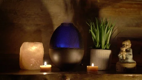 Aroma electric oil diffuser lamp, candles on wooden table in room. 4k. Stock Footage 129298656