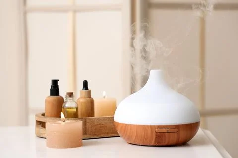 Aromatherapy diffuser with essential oils and lit candles creating a relaxing Stock Photos