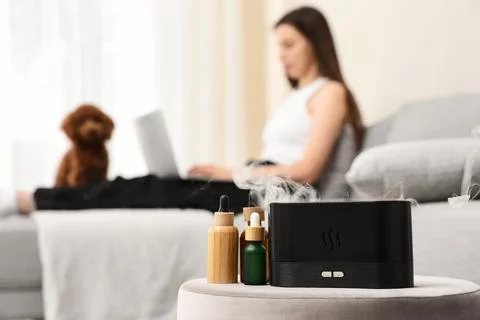 Aromatherapy diffuser with essential oils and a woman working on a laptop wit Stock Photos