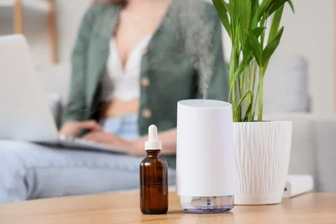 Aromatherapy essential oil diffuser and dropper bottle on table with woman us Stock Photos