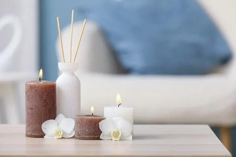 Aromatherapy reed diffuser with lit candles and white orchid flowers on a woo Stock Photos