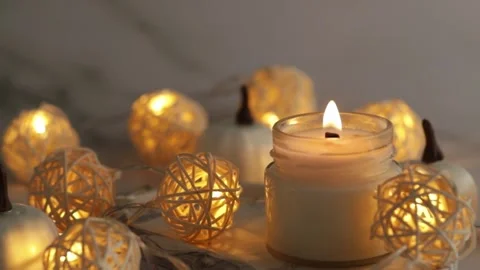 Aromatic burning candle on marble tray with pumpkins and warm lights, cozy .. Stock Footage 253576195