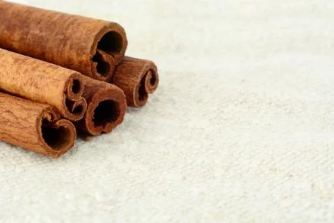 Aromatic close up set of cinnamon on white fibre material like flax Foto stock