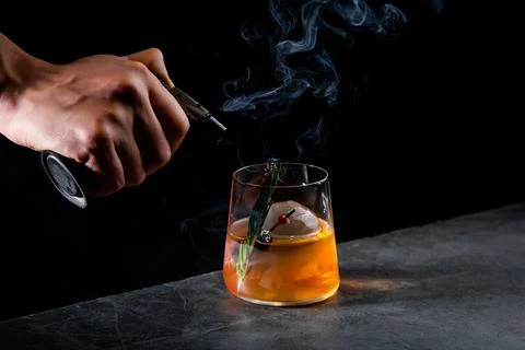 Aromatic cocktail with a sprig of pine needles and round ice on a dark Stock Photos