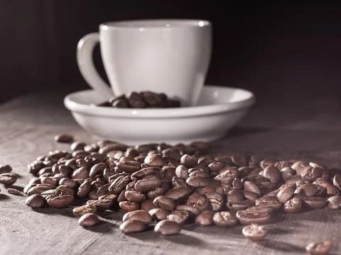 Aromatic coffee cup with foam surrounded by freshly roasted coffee beans Stock Photos