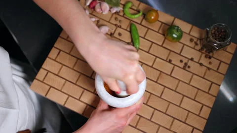 Aromatic flavours in white stone grinding bowl, person using pestle for crushing Stock Footage 228684312