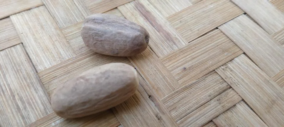Aromatic Nutmeg Kernels on Textured Bamboo Mat Stock Photos
