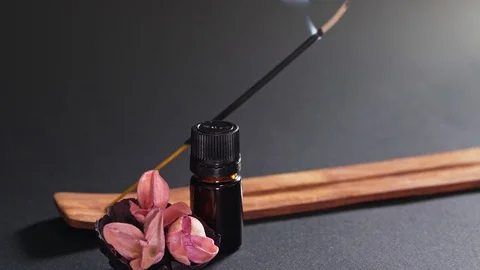 Aromatic oil in a black small jar, flowers and steaming incense. A static shot Stock Footage 125334945