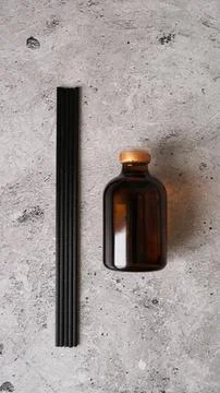Aromatic reed diffuser bottle with black sticks on a dark marble background. Stock Photos