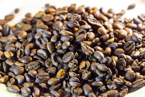 Aromatic roasted coffee beans pile on white surface for brewing delicious Фото