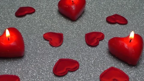 Around the burning candles in the shape of hearts are red fabric hearts Stock Footage 169761909