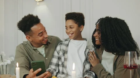Around the dinner table, an African American family shares laughter while Stock Footage 292092724