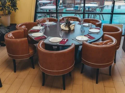 Around a large round table are leather round chairs near a window overlooking a Stock Photos