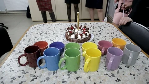 Around the white table with a cake and colored cups are people Stock Footage 92331183