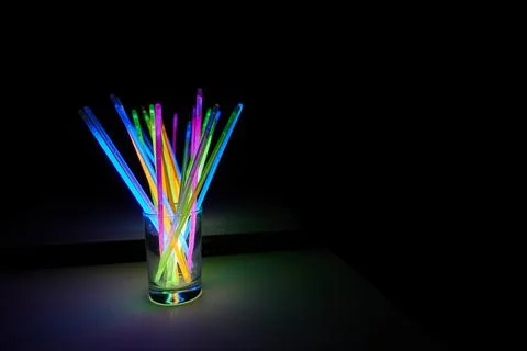 Arrangement of multi-colored glow sticks against a black background Foto stock