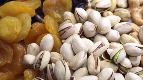 The arrangement showcases an array of dried fruits and assorted nuts on a white Stock Footage 292757072